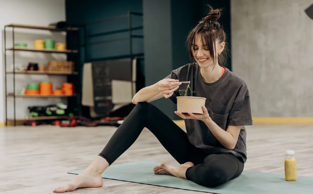 Mujer disfrutando de una ensalada después de entrenar, ejemplo de una alimentación equilibrada tras el ejercicio