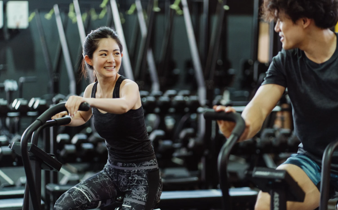 Pareja entrenando en máquinas de cardio retomando la rutina de ejercicio de forma constante y progresiva