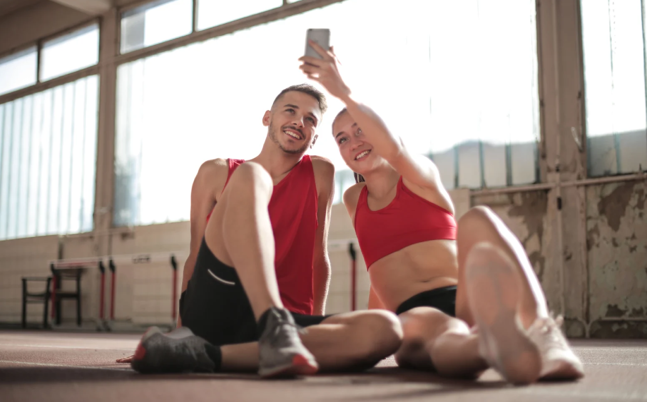 Pareja sonriente en el gimnasio durante su vuelta progresiva al ejercicio tras el verano