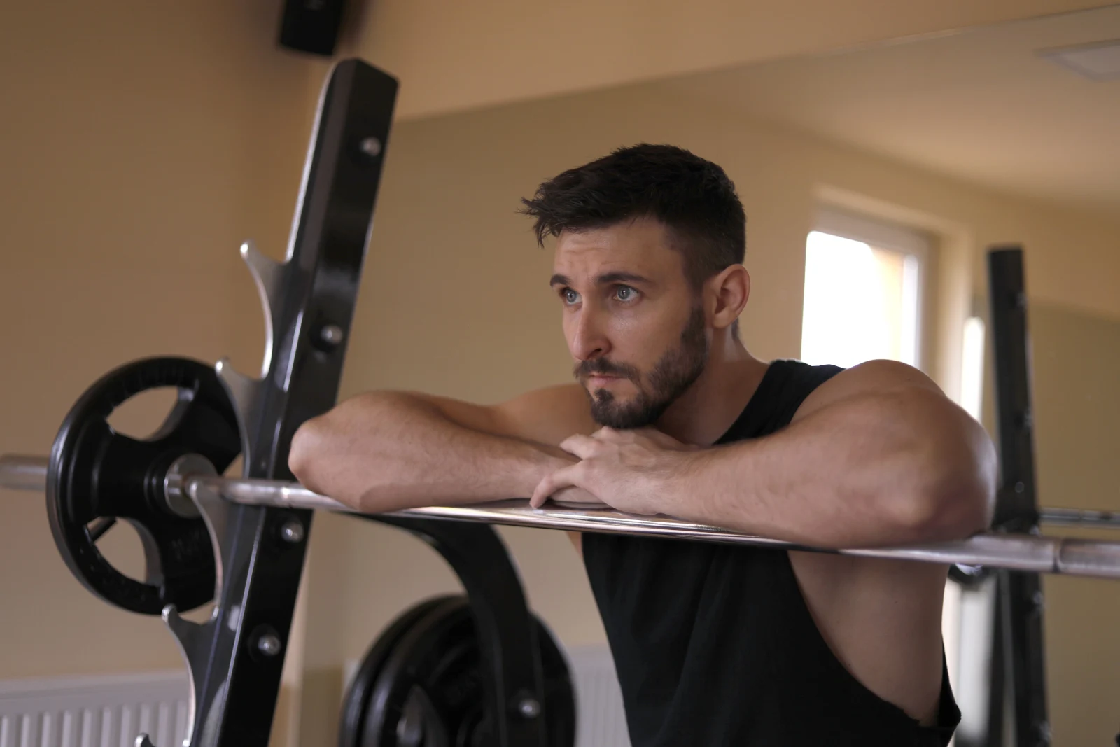 Hombre descansando tras un entrenamiento en el gimnasio, recuperando fuerzas después del ejercicio.