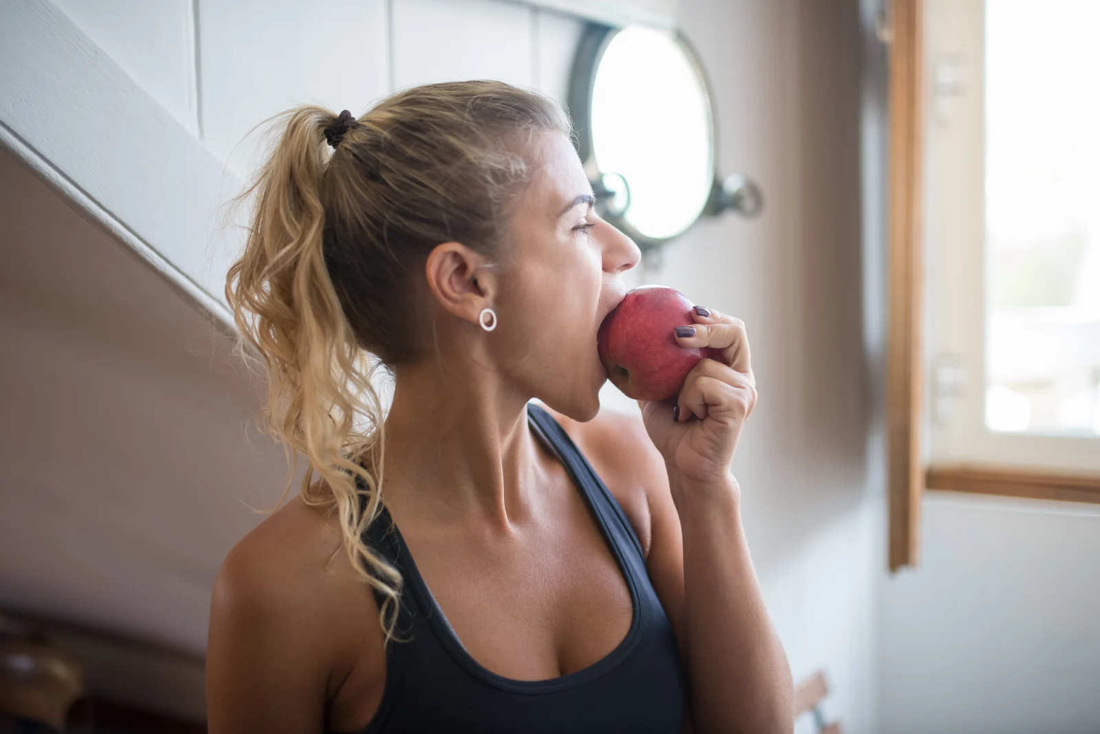 Mujer comiendo una manzana como tentempié saludable después del entrenamiento.